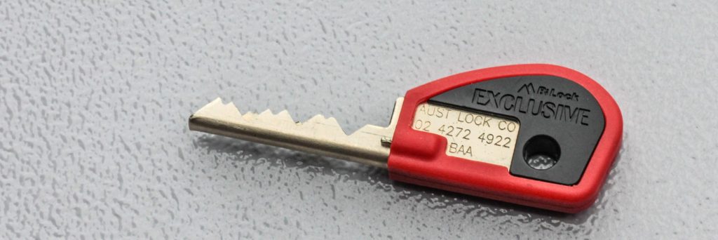 Close up of a restricted key with red grip on a grey background