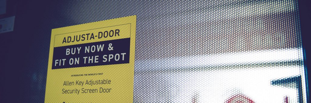 Close up of black security door mesh with a yellow sign on it